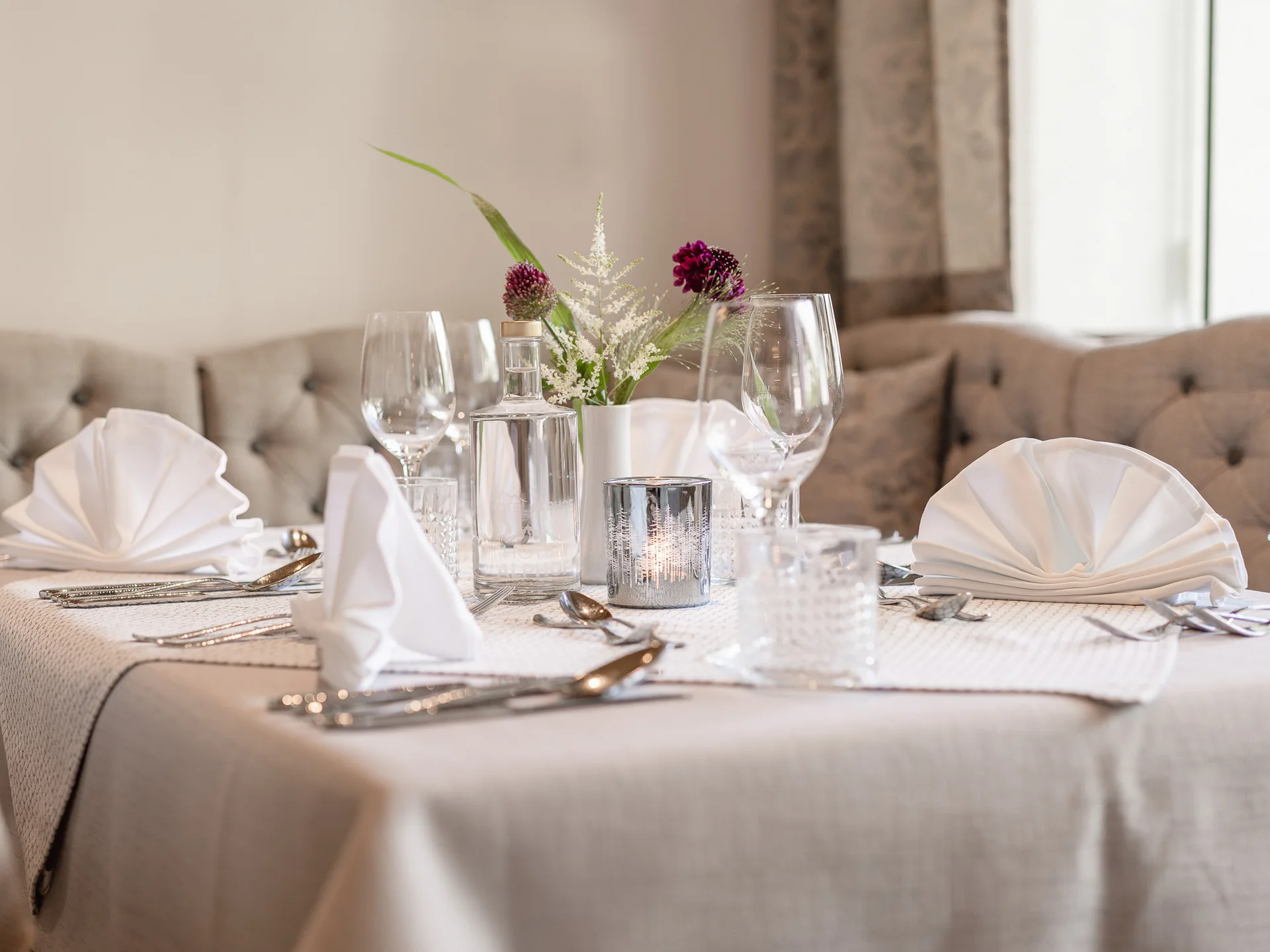 Alphof | genuine indulgence at a gourmet hotel in Tyrol Festively set restaurant table with flowers, wine glasses and folded napkins