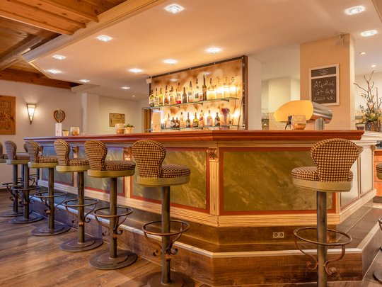 Ein feines Wellnesshotel in Fulpmes Gemütliche Bar mit Holztheke und gepolsterten Barhockern