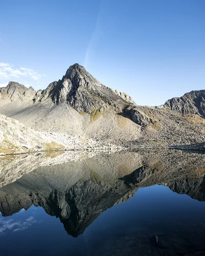 Hotel Alphof | your basecamp for walking holidays in Austria Jagged mountain lake reflecting rocky peaks beneath a blue sky