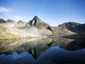 Hotel Alphof | your basecamp for walking holidays in Austria Jagged mountain lake reflecting rocky peaks beneath a blue sky