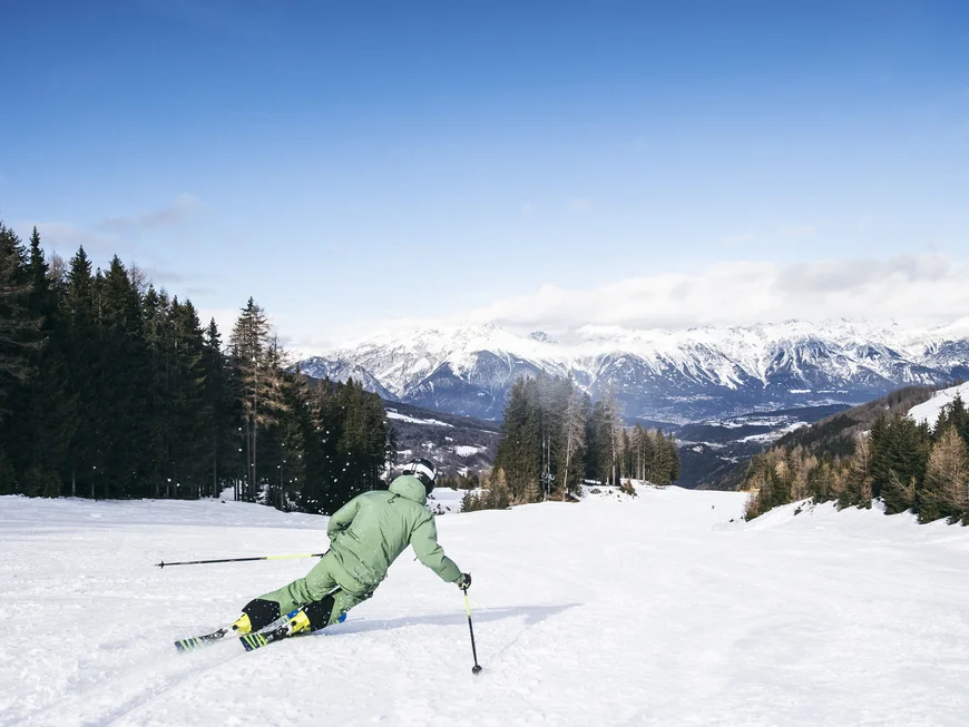 Skier descending a snowy slope with a mountain panorama