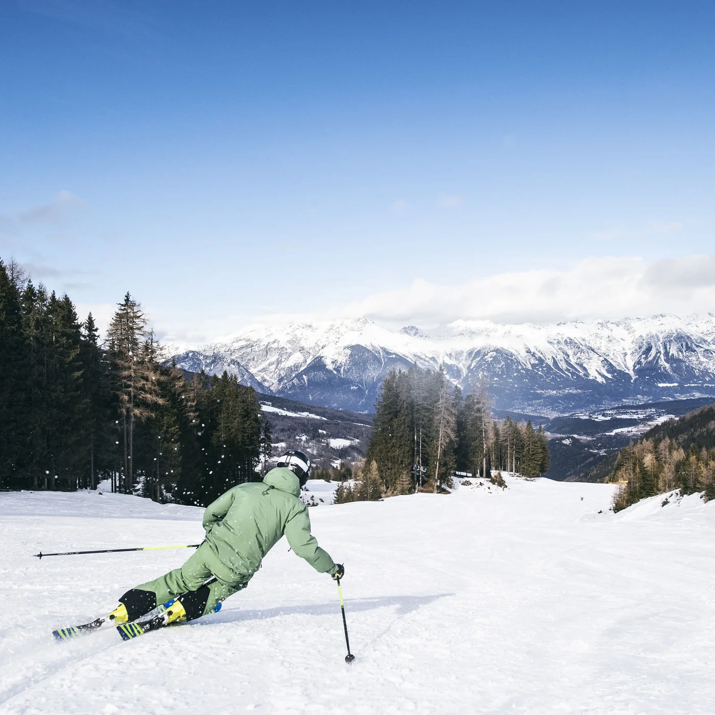 Skier descending a snowy slope with a mountain panorama