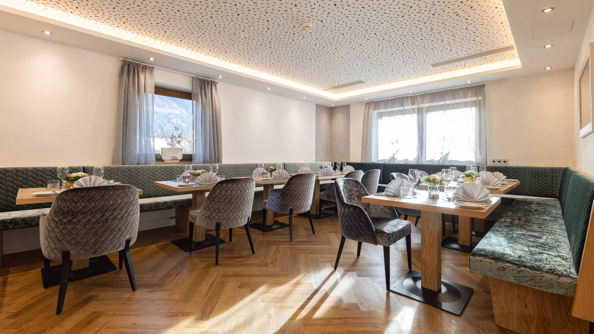 Bright dining room with set tables, upholstered chairs and bench seating