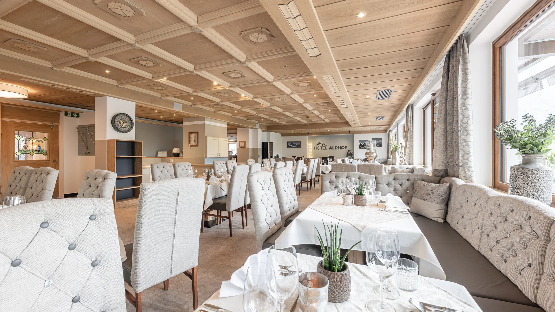 Bright hotel dining room with set tables, upholstered chairs and large windows
