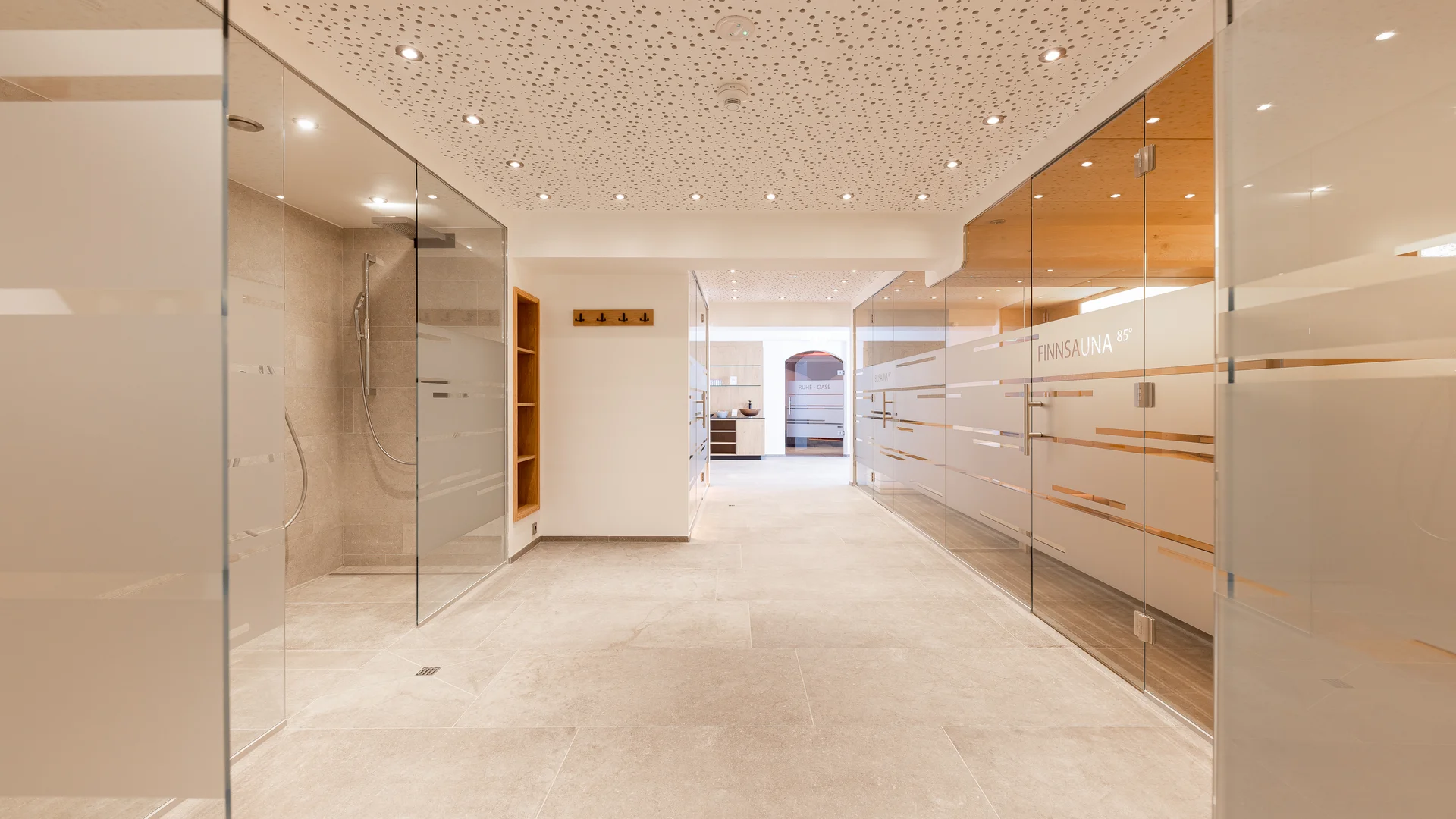 Bright wellness area with glass showers, wooden elements and tiled floor