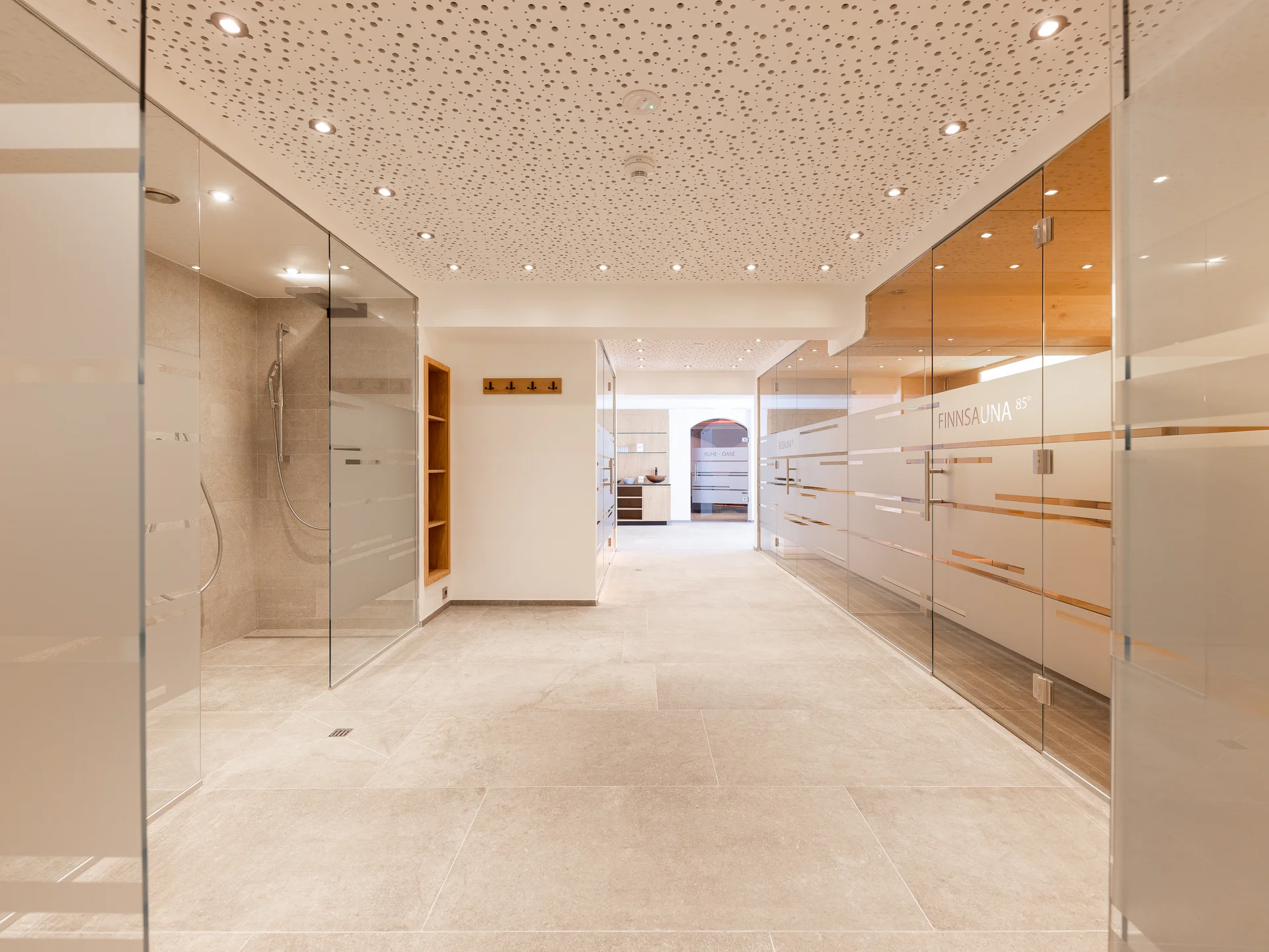 The modern AlpSpa at your spa hotel in Tyrol Bright wellness area with glass showers, wooden elements and tiled floor