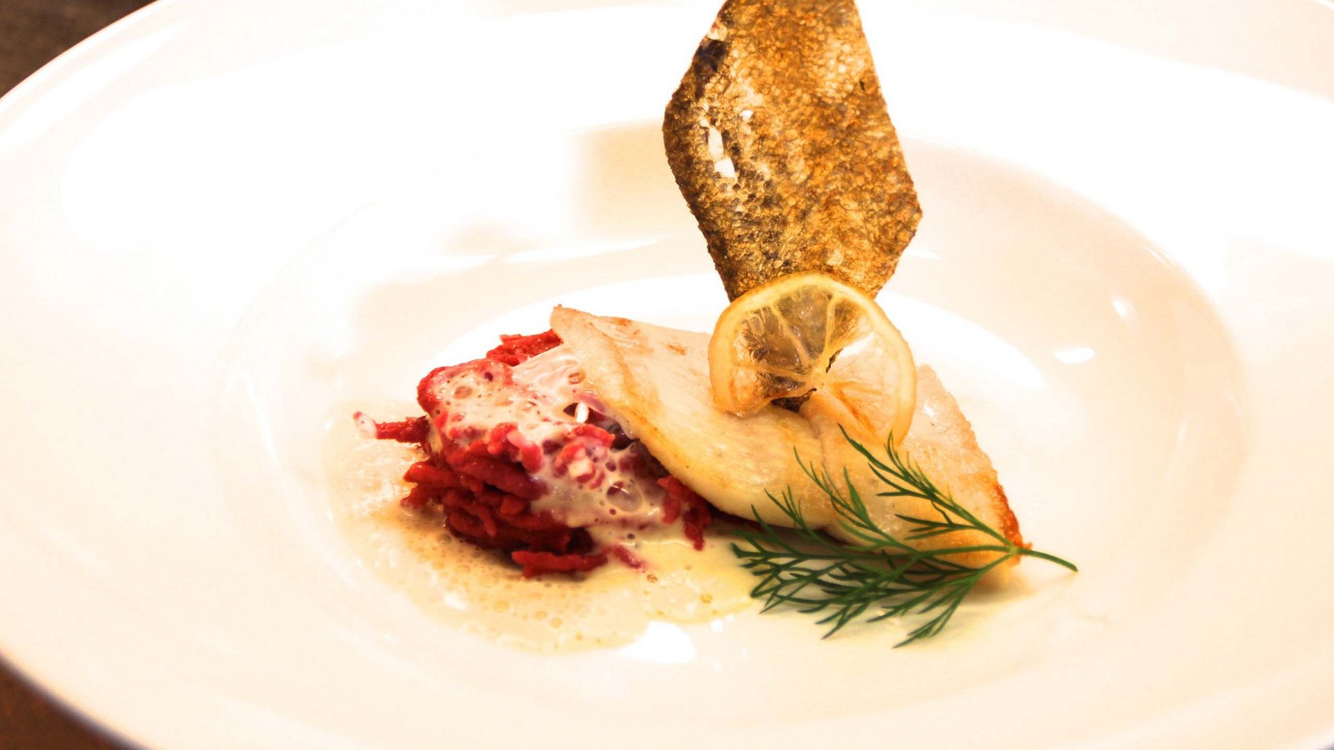 Ein feines Wellnesshotel in Fulpmes Fein angerichteter Fisch mit roter Beilage, Zitronenscheibe, Dill und knuspriger Garnitur