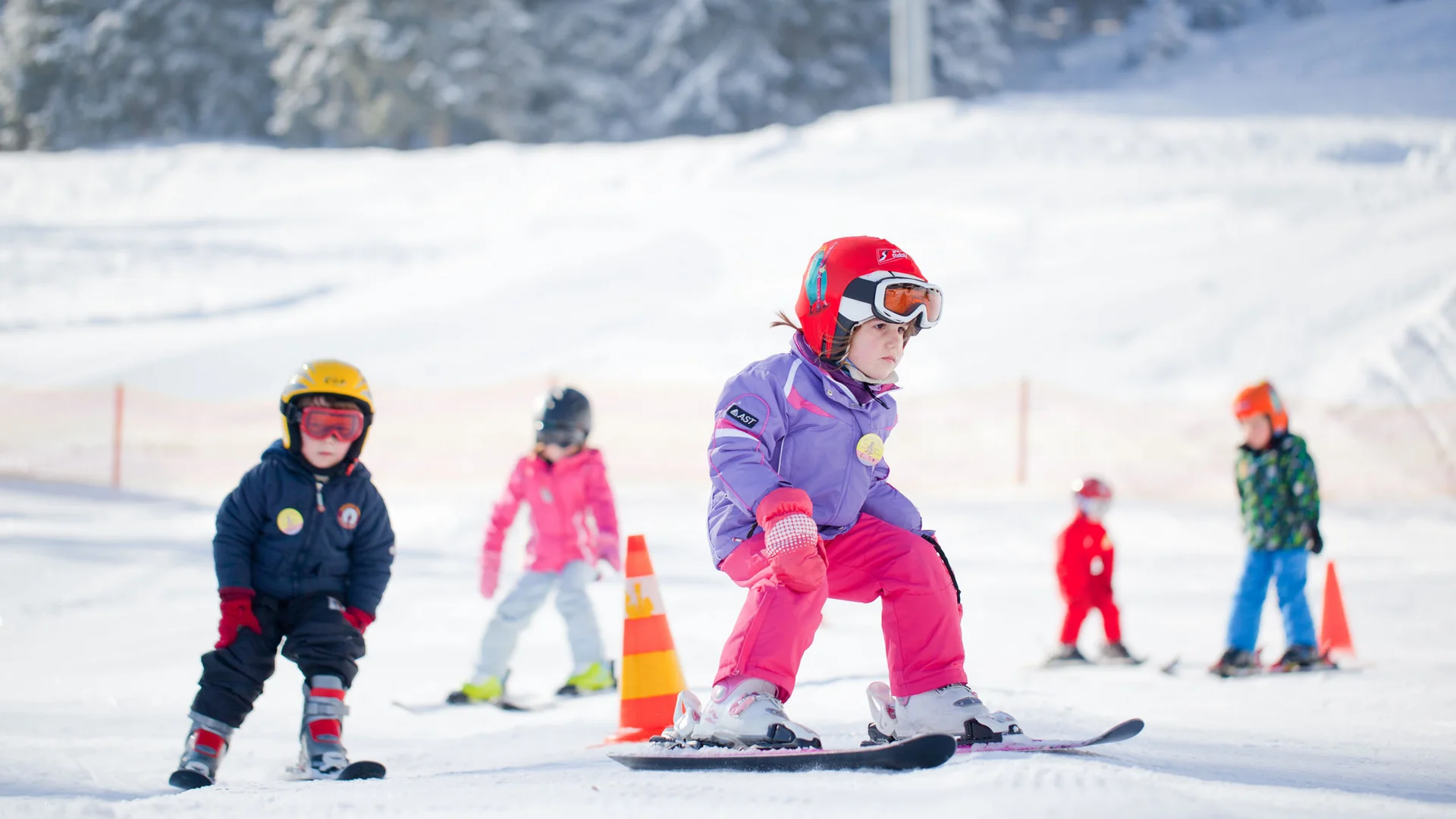 Children snowboarding on a snowy slope
