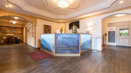 Einblicke in unser Hotel im Stubaital in Fulpmes Hotel Alphof Rezeption mit Bergmotiven und Holzelementen