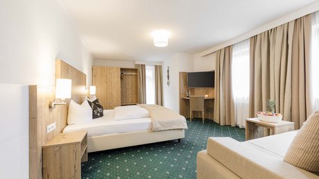Einblicke in unser Hotel im Stubaital in Fulpmes Helles Hotelzimmer mit Doppelbett, Sitzbereich, TV und großem Fenster