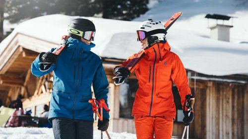 Summer or winter holiday in Tyrol: Hotel Alphof in Fulpmes Two skiers in blue and orange gear standing in front of snowy cabin