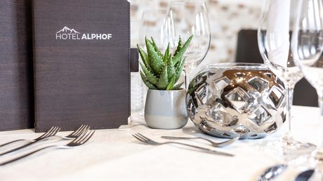 Einblicke in unser Hotel im Stubaital in Fulpmes Eleganter Tisch mit Hotel Alphof Karte, Pflanze und geschliffenen Gläsern