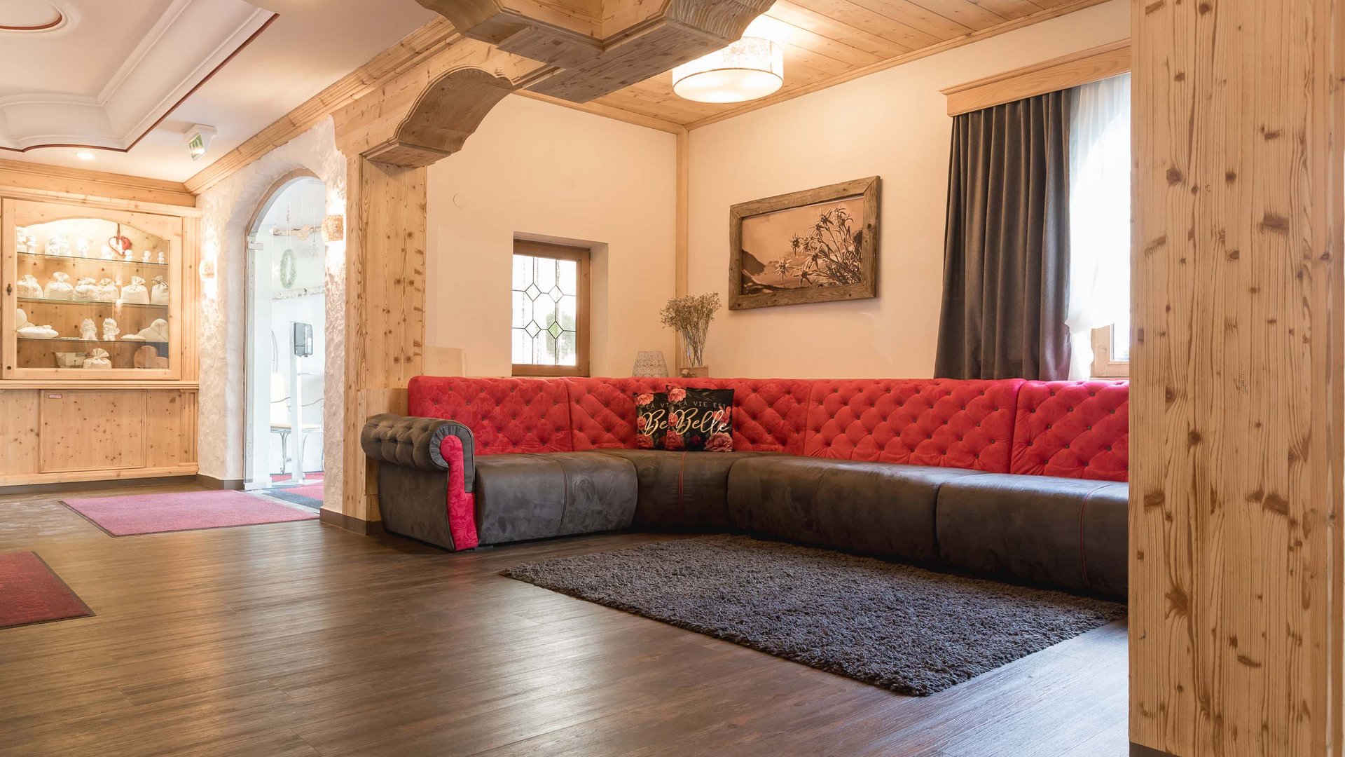My hotel in Fulpmes in Stubaital Cozy living room with red and gray corner sofa and wooden beam ceiling
