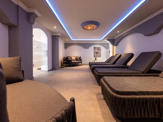 4-Sterne-Hotel Stubaital: Ihr Alphof erwartet Sie! Innenansicht eines modernen Spa-Wartebereichs mit Liegestühlen und Sofa