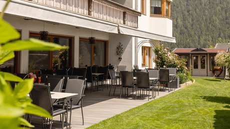 Einblicke in unser Hotel im Stubaital in Fulpmes Leere Terrasse mit Stühlen und Tischen neben einem Gebäude und einem Garten