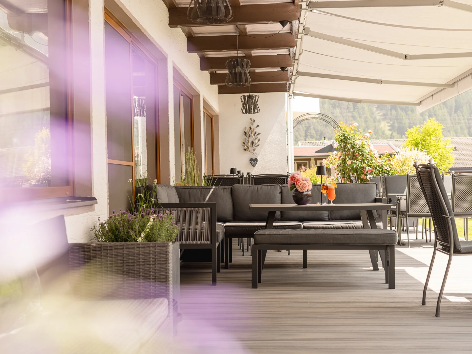 Der Alphof | Ihr Hotel in Fulpmes Überdachte Terrasse mit Sitzmöbeln, Pflanzen und Bergblick