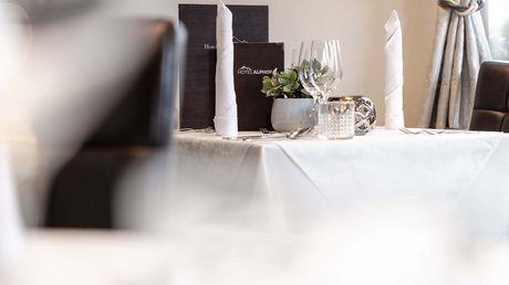 Einblicke in unser Hotel im Stubaital in Fulpmes Eleganter gedeckter Tisch im Hotelrestaurant mit Menükarten und dekorativen Elementen