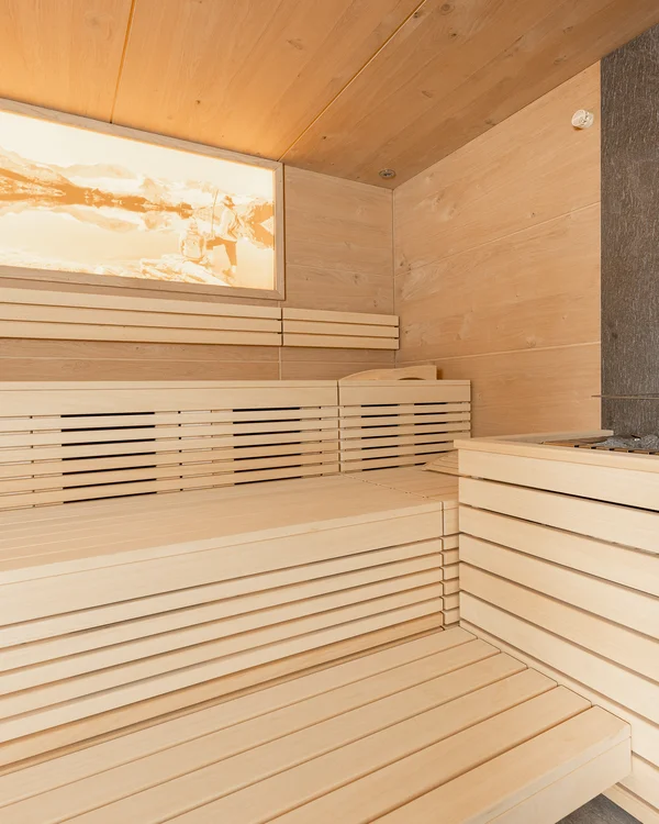 Bright wood sauna with benches, sauna heater and abstract wall artwork