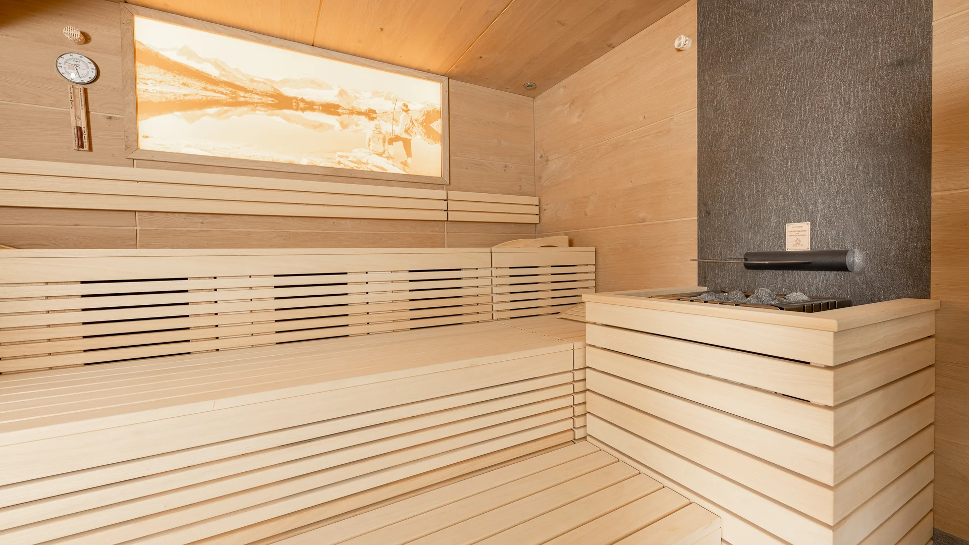 Bright wood sauna with benches, sauna heater and abstract wall artwork
