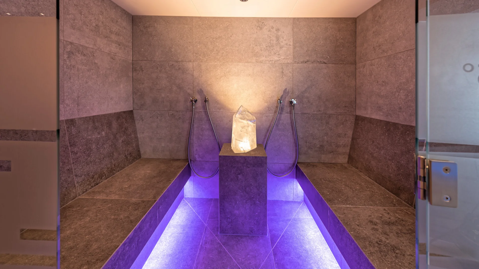 Steam room with natural stone walls, benches and purple lighting