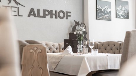 Einblicke in unser Hotel im Stubaital in Fulpmes Eleganter gedeckter Tisch im Hotel Alphof mit Bergbildern an der Wand