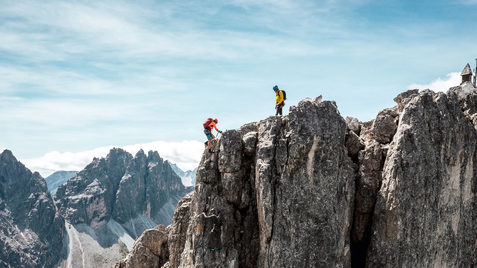 Two climbers on a rugged mountain ridge above an alpine landscape