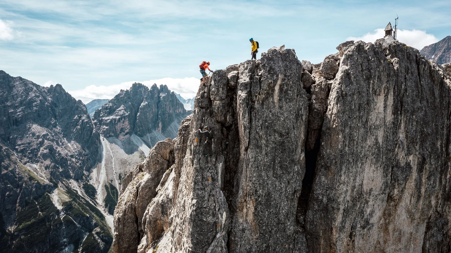 Two climbers on a rugged mountain ridge above an alpine landscape