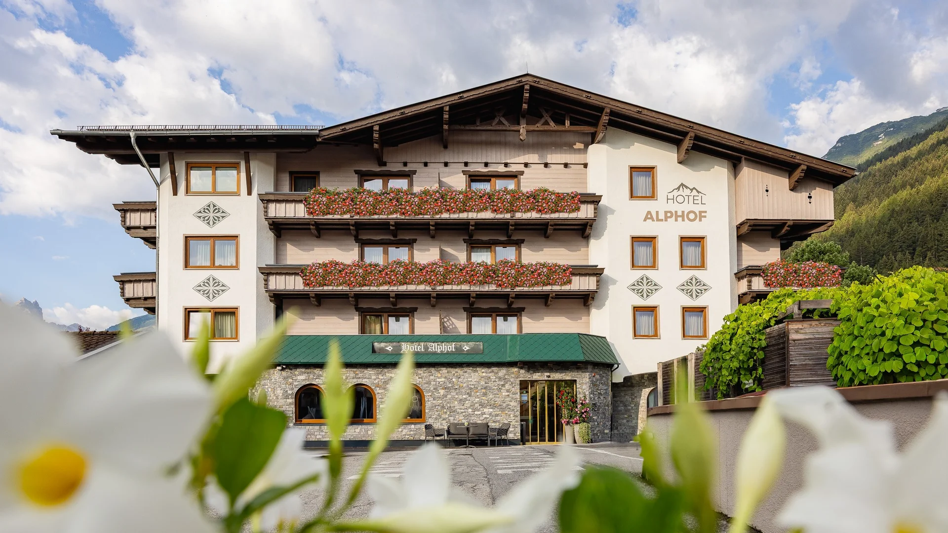 Hotel Alphof with flower-filled balconies against an alpine mountain backdrop