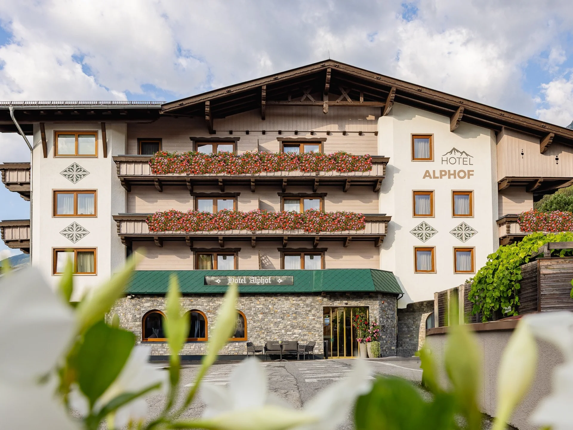 Der Alphof | Ihr Hotel in Fulpmes Hotel Alphof mit blumengeschmückten Balkonen vor alpiner Bergkulisse