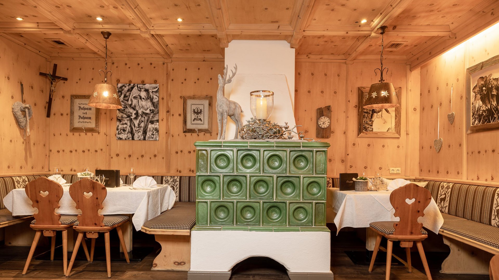 Hotel Alphof: ein Gourmethotel in Tirol Traditioneller Gastraum mit grüner Kachelofen, Holzmöbeln und gemütlicher Eckbank