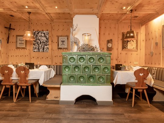Ein feines Wellnesshotel in Fulpmes Traditioneller Gastraum mit grüner Kachelofen, Holzmöbeln und gemütlicher Eckbank