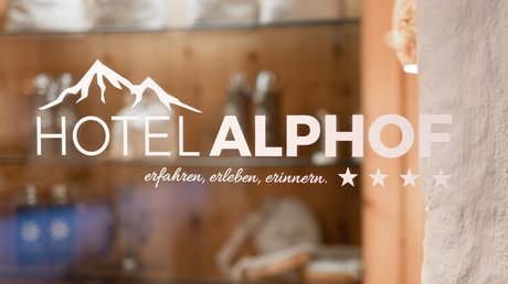 Einblicke in unser Hotel im Stubaital in Fulpmes Logo und Schriftzug Hotel Alphof mit Bergsymbol auf Glasfläche