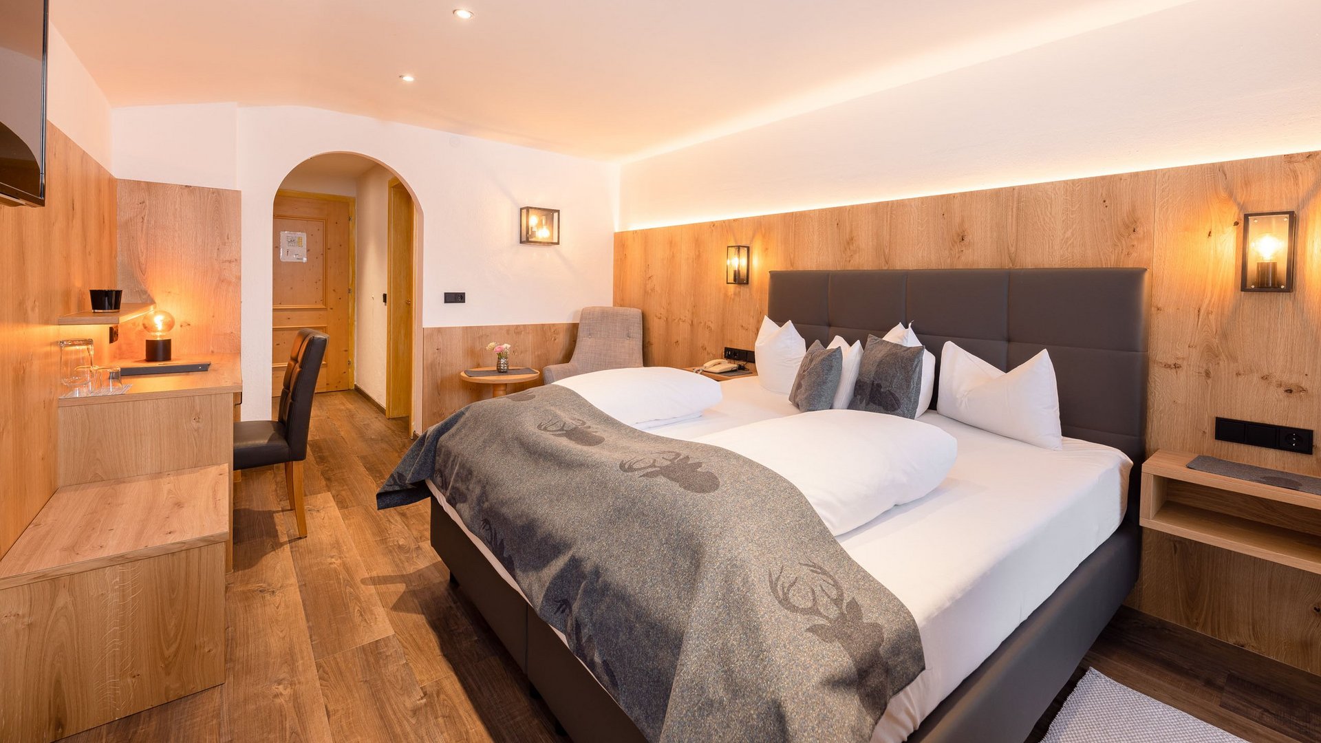 My hotel in Fulpmes in Stubaital Modern hotel room with double bed, wood paneling, and TV