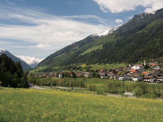 Ski slope or summer toboggan run? Stubai offers it all! Village in a green valley with mountains and snow-capped peaks in the background