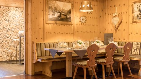 Einblicke in unser Hotel im Stubaital in Fulpmes Gemütlicher holzverkleideter Essbereich mit eingedecktem Tisch und Herzstühlen