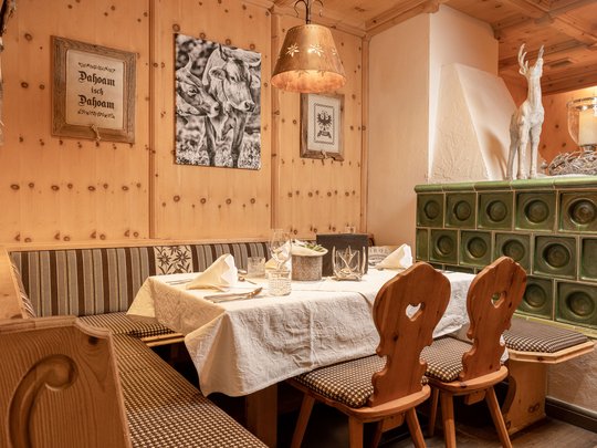 Romantik in den Bergen Gemütliche Rustik-Ecke mit Holzmöbeln, Kachelofen und Kuhbildern an der Wand