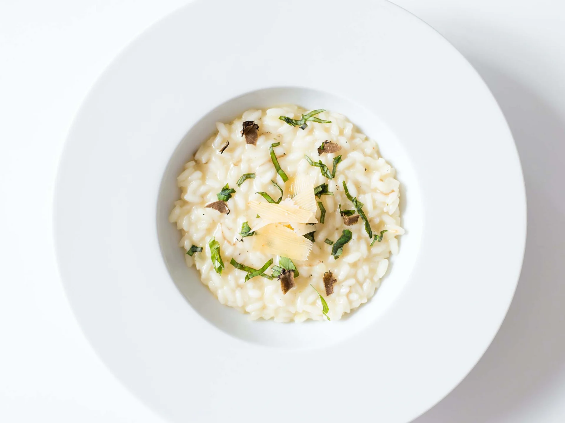 Alphof | genuine indulgence at a gourmet hotel in Tyrol Creamy risotto with herbs, cheese shavings and mushroom pieces on a white plate
