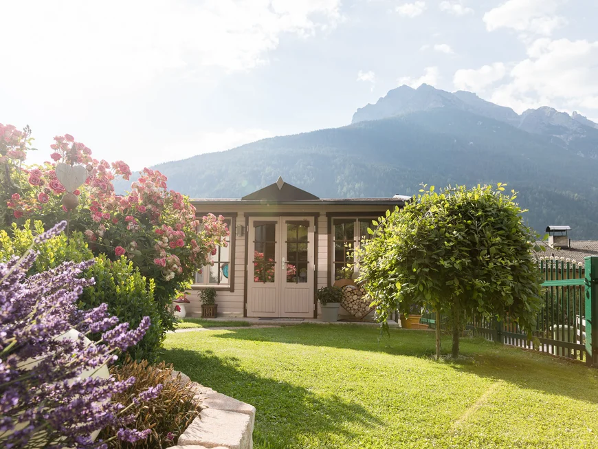Garden and terrace at Hotel Alphof in Fulpmes, Tyrol Garden with flowers, a garden house and mountain panorama in the background