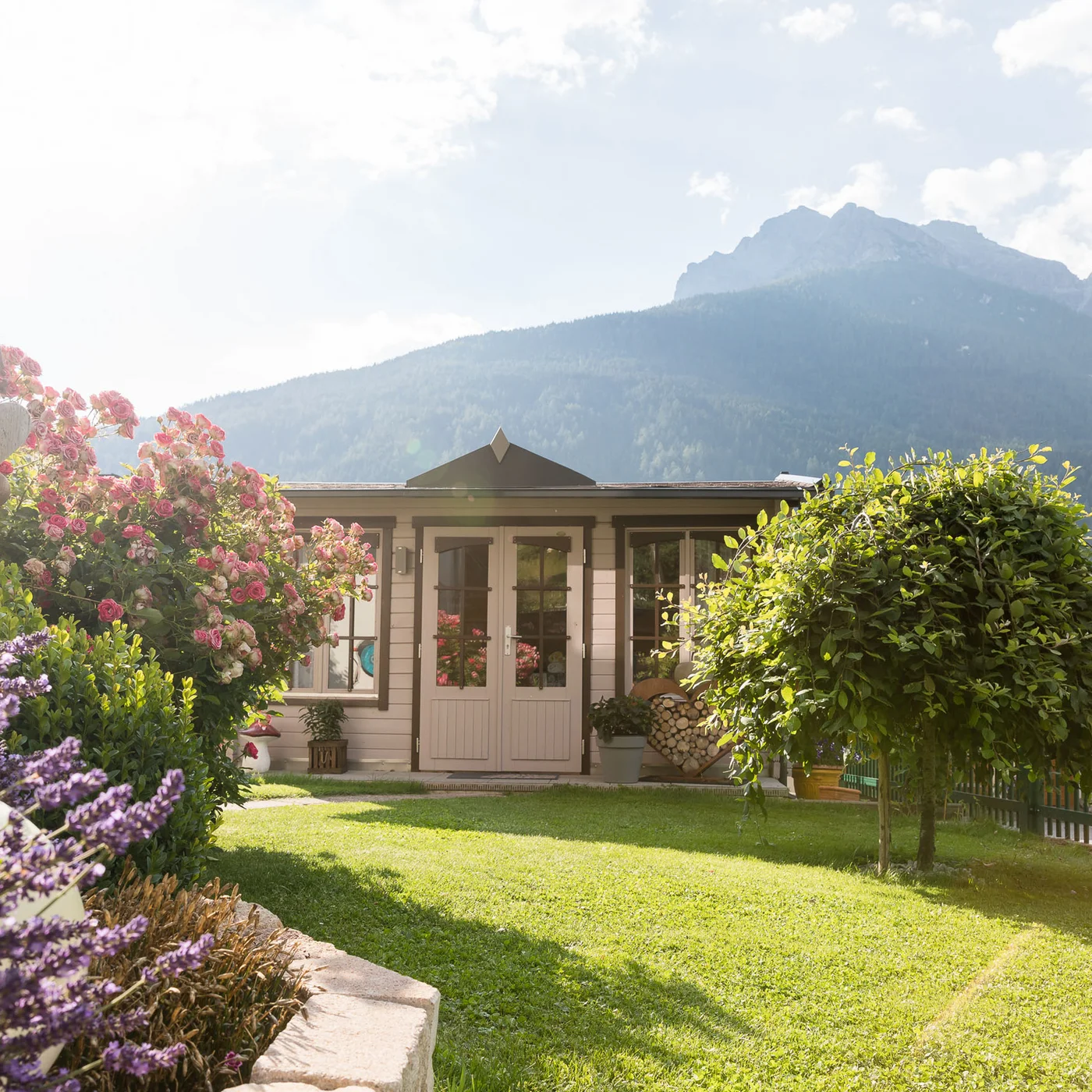 Garden and terrace at Hotel Alphof in Fulpmes, Tyrol Garden with flowers, a garden house and mountain panorama in the background