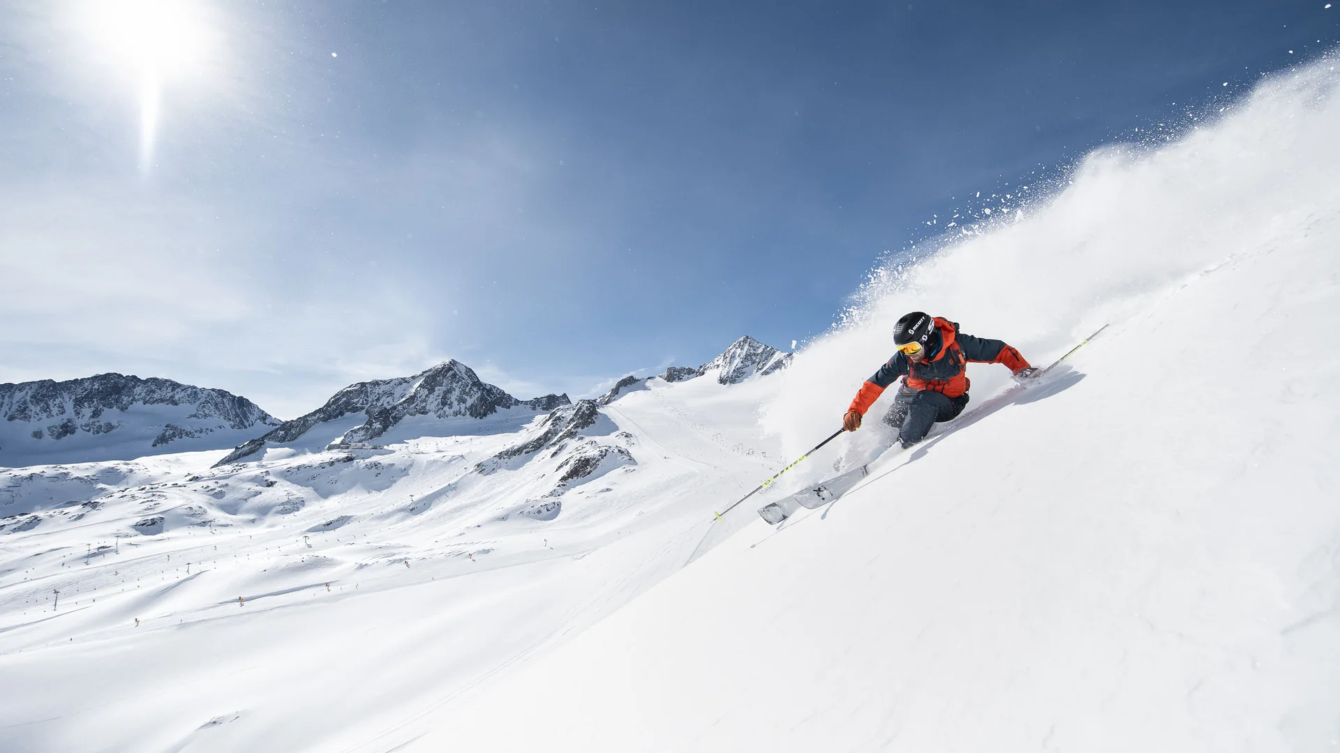 Skier in a red jacket skiing through a snowy mountain landscape