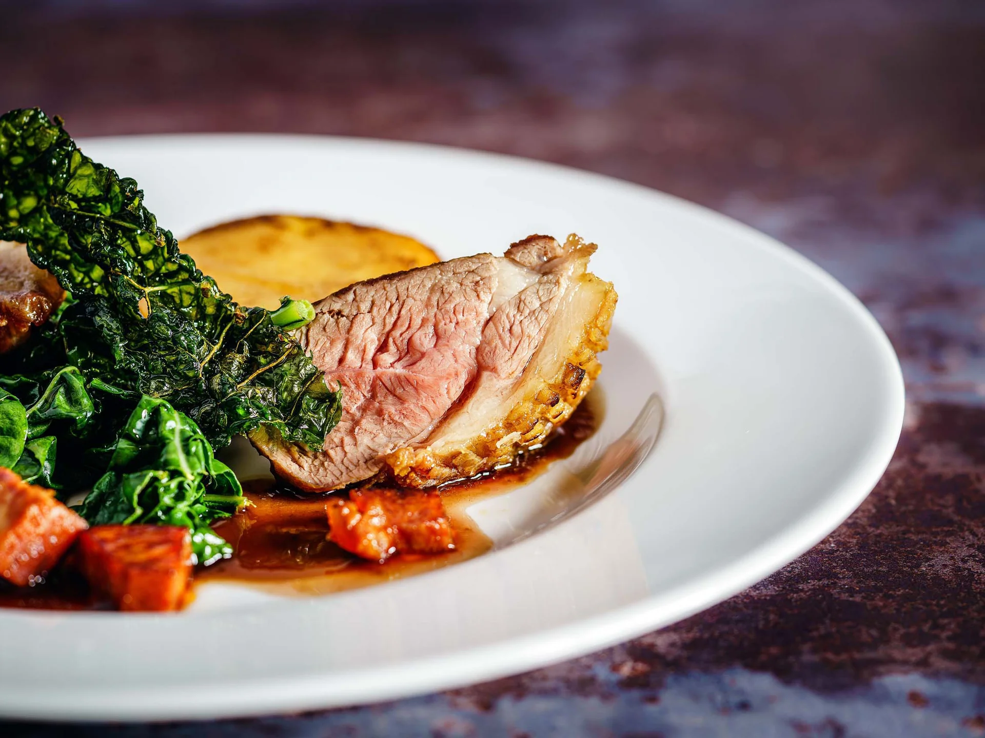 Alphof | genuine indulgence at a gourmet hotel in Tyrol Sliced pink roast meat with leafy greens, vegetable cubes and sauce on a plate