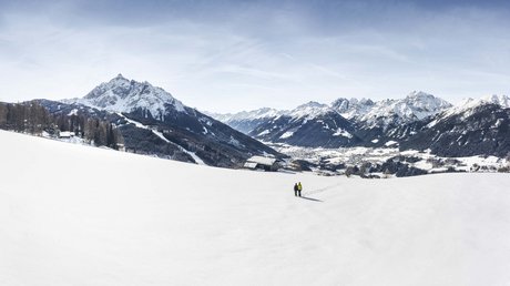Einblicke in unser Hotel im Stubaital in Fulpmes Zwei Personen wandern durch ein schneebedecktes Tal in den Alpen