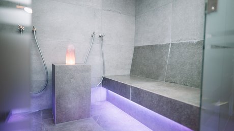 Einblicke in unser Hotel im Stubaital in Fulpmes Moderner Saunaraum mit grauen Fliesen und violetter LED-Beleuchtung