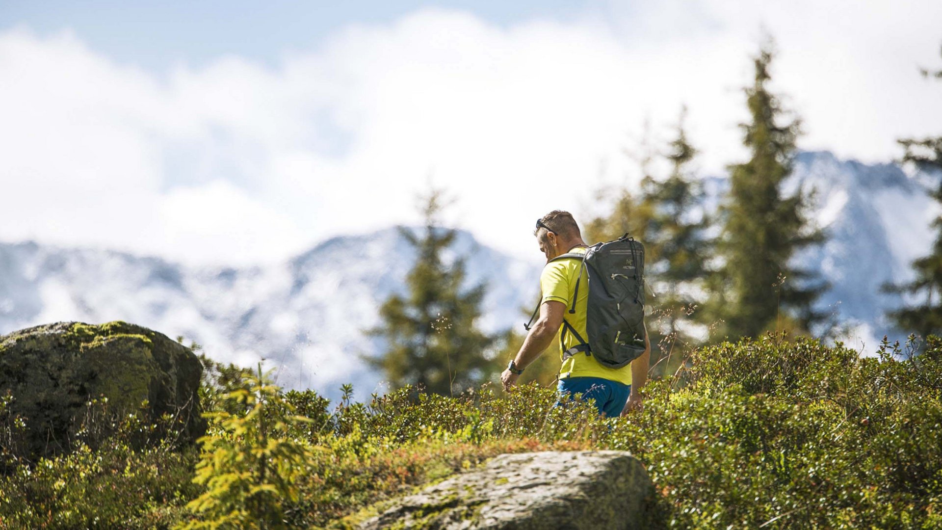 Family hotel in Austria: experience Tyrol at Alphof Man hiking in the mountains with a backpack on a sunny day