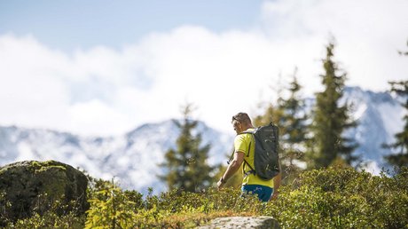 Einblicke in unser Hotel im Stubaital in Fulpmes Mann mit Rucksack wandert in den Bergen bei sonnigem Wetter