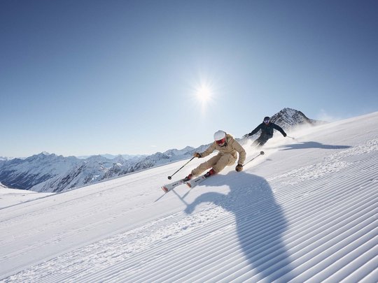 Sommerurlaub im Stubaital: nicht ohne meine Stubai Super Card Zwei Skifahrer fahren bei sonnigem Wetter auf frisch präparierter Piste in den Bergen