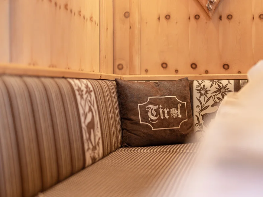 Inclusive services | Hotel Alphof in Fulpmes Rustic sofa with striped upholstery and cushion bearing the word Tirol