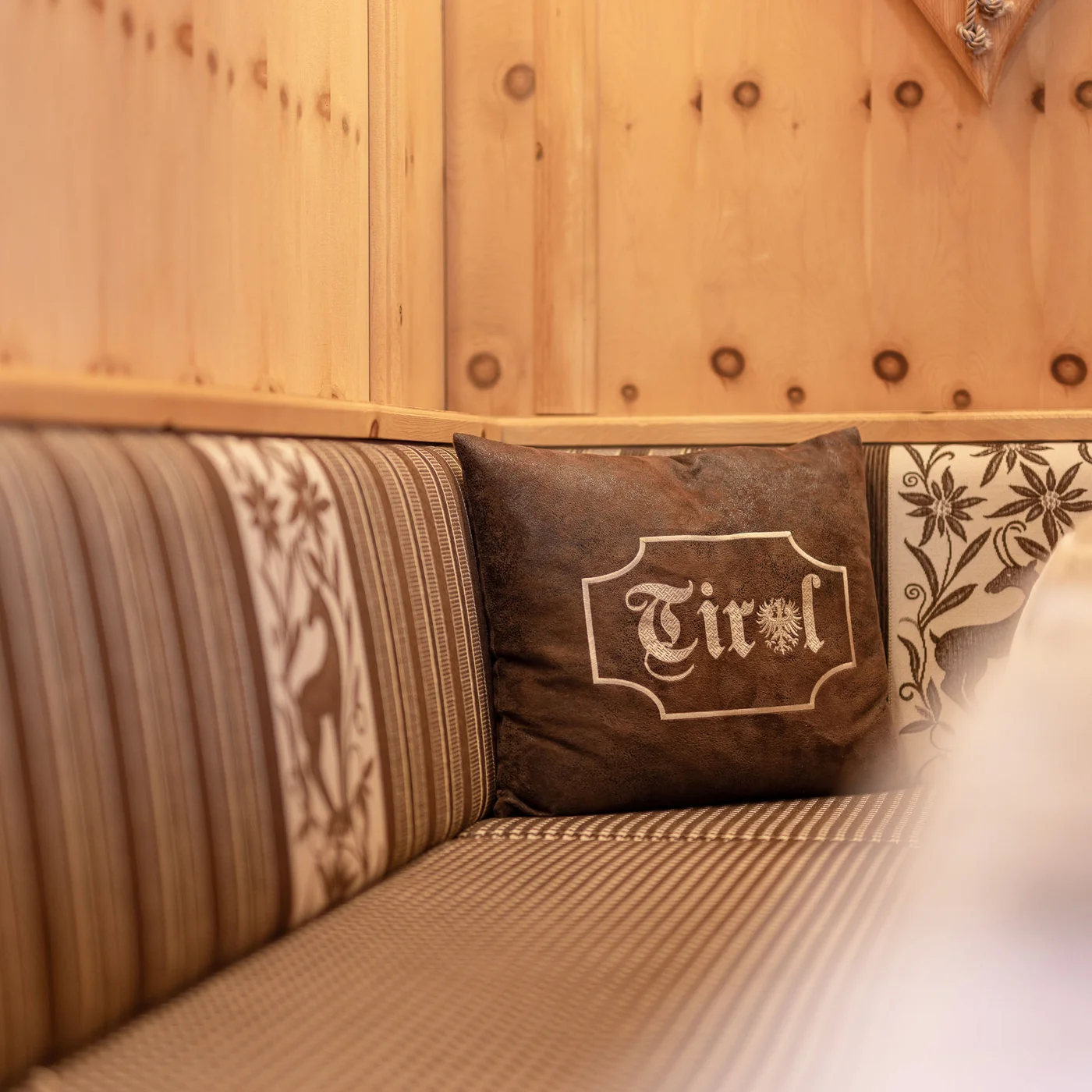 Inclusive services | Hotel Alphof in Fulpmes Rustic sofa with striped upholstery and cushion bearing the word Tirol