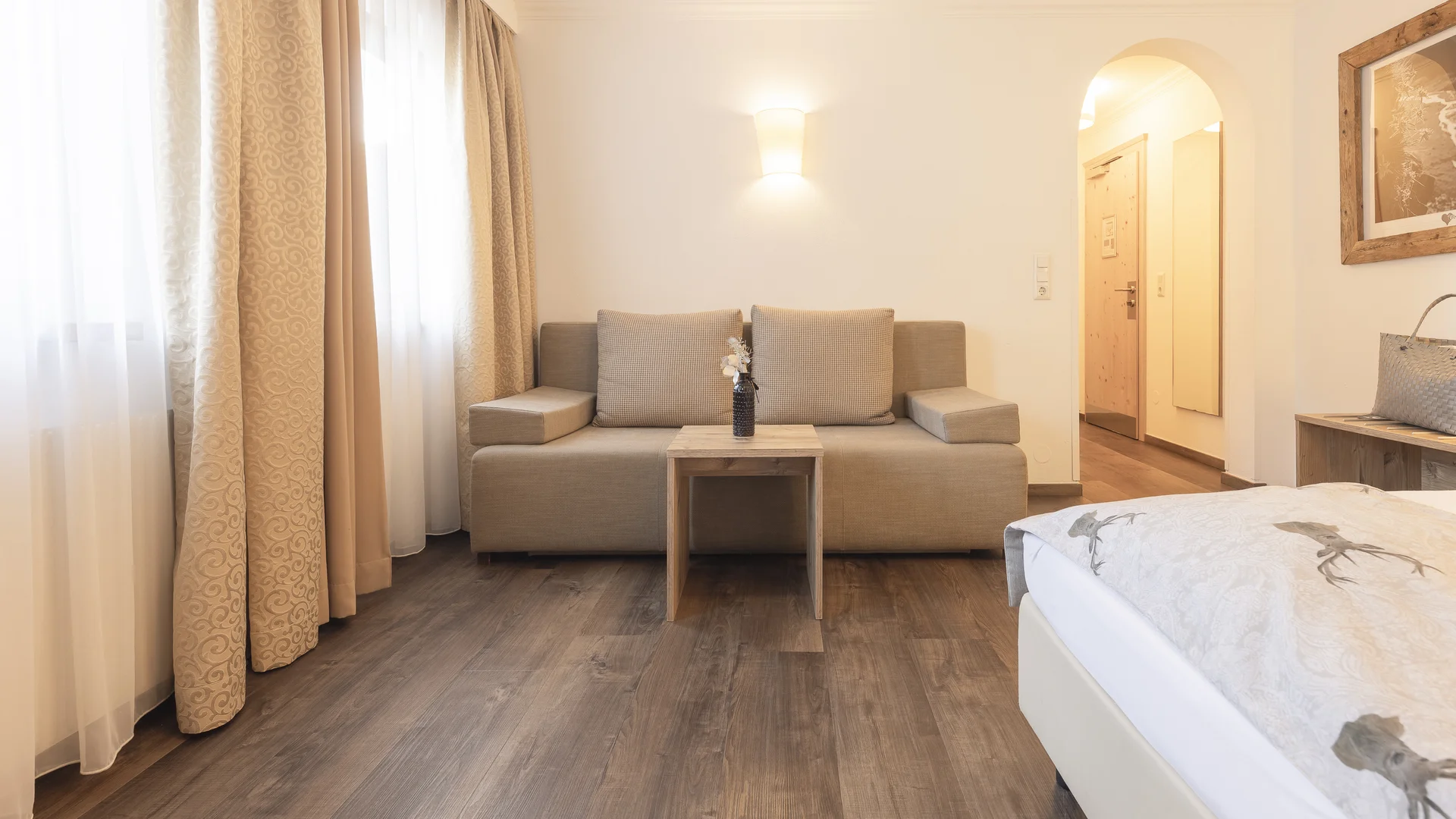 Bright hotel room with sofa, coffee table and bed