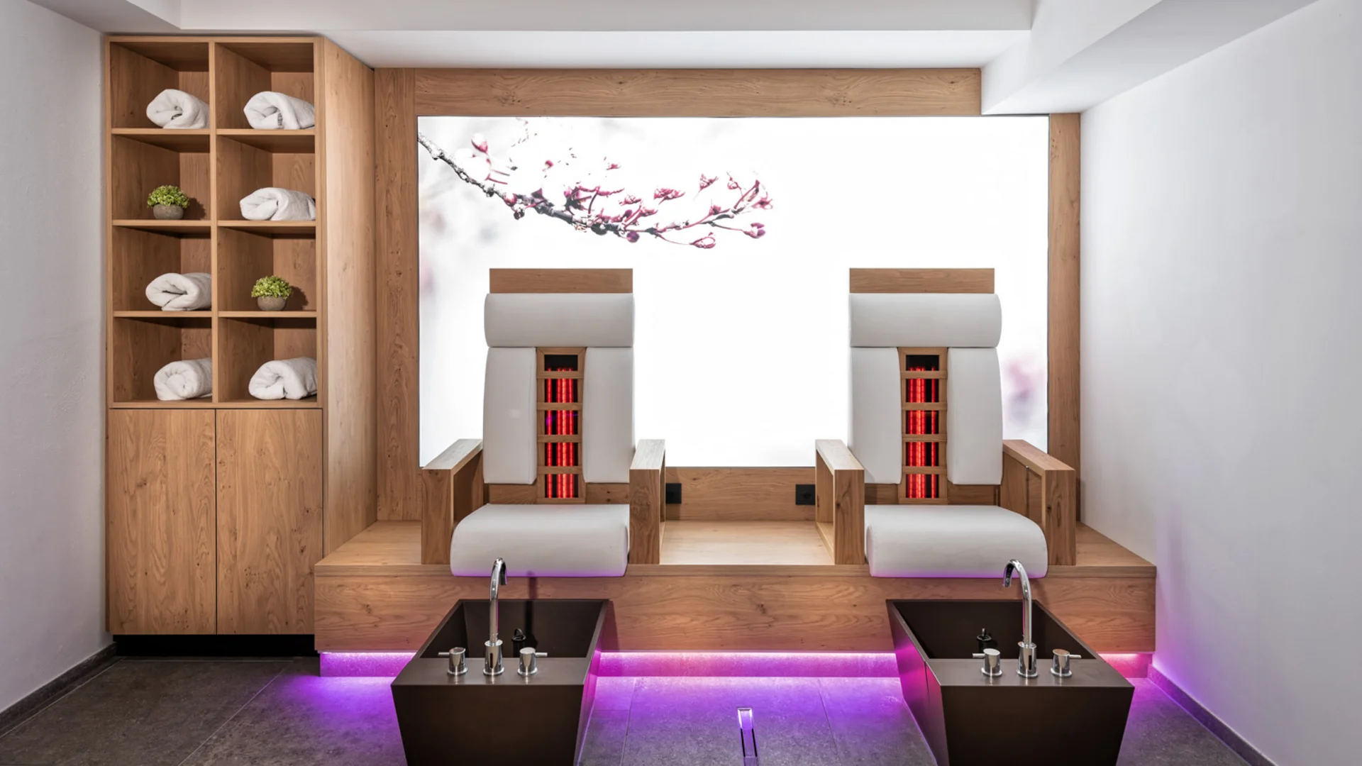 Modern wellness room with two heated loungers, foot baths and towel shelving